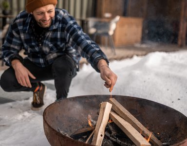 Mann zündet Feuer in Feuerstelle im Schnee an
