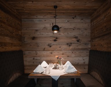 Gedeckter Tisch in gemütlicher Holzecke mit Blumen und Beleuchtung
