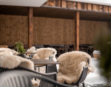 Stühle mit Fellüberzügen auf Terrasse eines Cafés bei kaltem Wetter