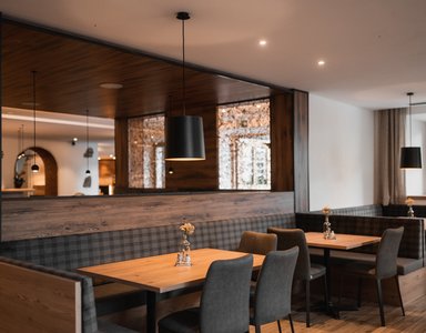 Gemütlicher Restaurantbereich mit Holztischen und gepolsterten Sitzbänken