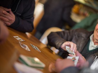 Anziani che giocano a carte a un tavolo di legno