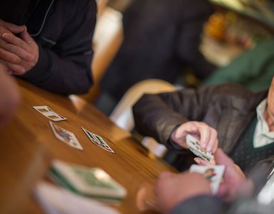 Ältere Menschen spielen Karten an einem Holztisch