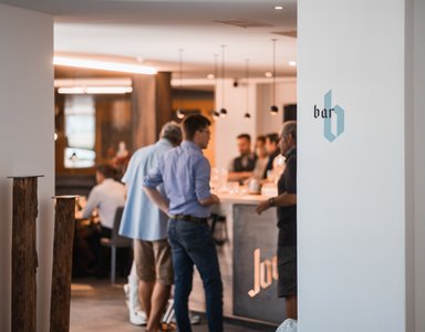 Menschen stehen an einer Bar in modernem Innenraum.