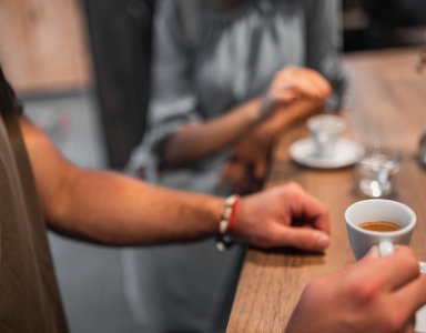 Menschen sitzen an einem Holztisch und trinken Espresso