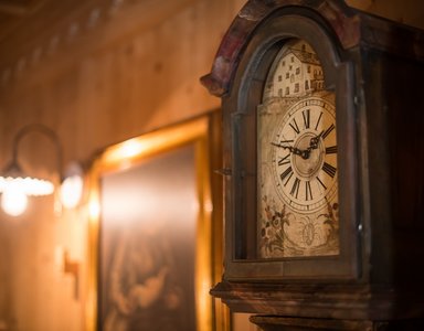 Close-up of an antique grandfather clock with Roman numerals and painted dial