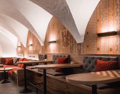 Moderne Lounge mit gewölbter Decke, Holztischen und roten Kissen