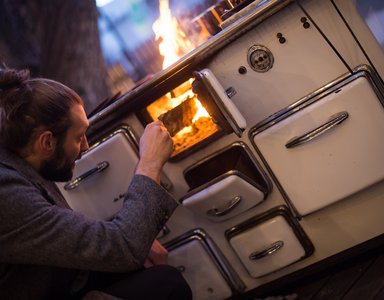 Mann macht Feuer in einem alten Holzofen im Freien