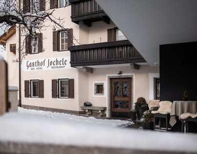 Gasthof Jochele mit verschneitem Eingangsbereich und gedecktem Außensitzbereich