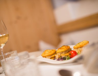 Drei kleine gefüllte Kartoffelpfannkuchen auf einem weißen Teller mit Salat und Tomate