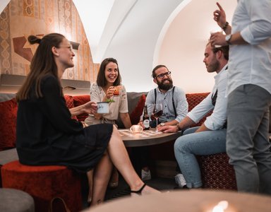 Fünf Freunde bei einem gemütlichen Treffen mit Getränken in einem Lounge-Bereich