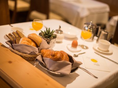 Breakfast table with rolls, croissants, egg, and orange juice
