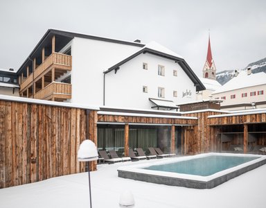 Außenpool in verschneitem Hotel mit Holzwänden und Bergkulisse