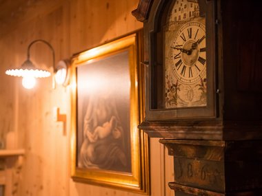 Vecchio orologio a pendolo e quadro in una stanza illuminata con pareti in legno