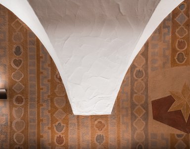 Weißes Gewölbe mit braunen Wandmalereien und geometrischen Mustern