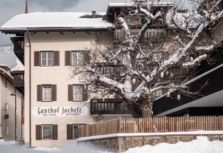 Gasthof Jochele in villaggio innevato con albero e recinzione di legno