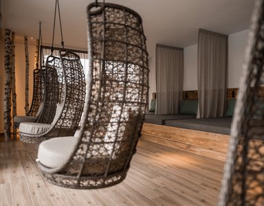 Moderner Relaxraum mit hängenden Korbsesseln und Holzboden
