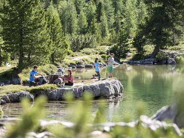 Kinder entspannen und spielen an einem klaren Bergsee im Sommer