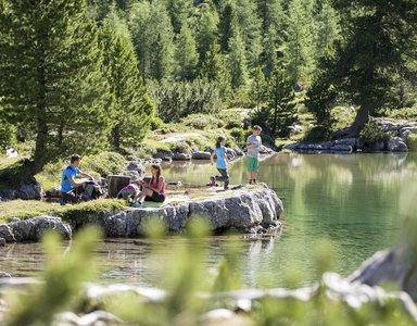 Kinder entspannen und spielen an einem klaren Bergsee im Sommer