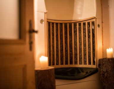 Gemütliche Saunaecke mit Holzbank, Heu und brennenden Kerzen