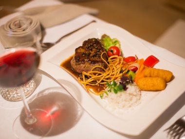 Gourmet steak with rice, vegetables, and red wine served in a restaurant