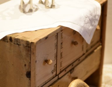 Alte Holzkiste mit weißen Stofftüchern bedeckt, auf hellen Boden