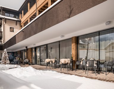 Außenbereich eines Cafés mit Tisch und Stühlen, umgeben von Schnee
