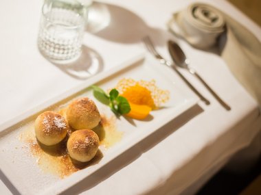 Three sweet dumplings with powdered sugar and fruit on white plate