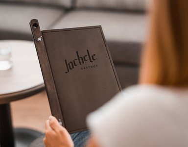 Person hält eine Speisekarte vom Gasthof Jochele