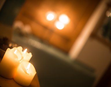 Brennende Kerzen auf einem Holzbrett mit warmem Hintergrundlicht