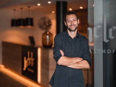 Uomo con le braccia incrociate in un'area reception moderna di una locanda