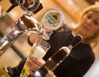Frau zapft ein Glas Forst Bier an einem Zapfhahn