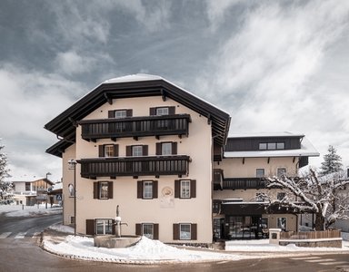 Schneebedecktes Haus mit Holzbalcon und winterlicher Landschaft