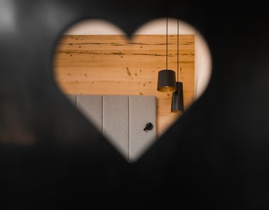 Blick durch herzförmigen Ausschnitt auf Wand aus Holz und gekoppelte Lampen