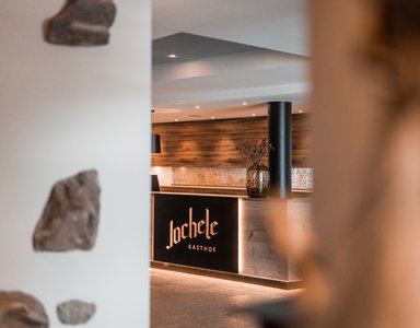 Empfangstresen im Gasthof Jochele mit Holzvertäfelung und Blumendeko