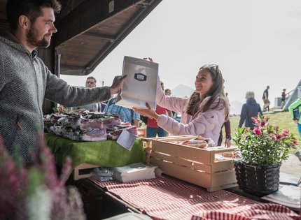 Woman buying fresh cured meats from a vendor at an outdoor market